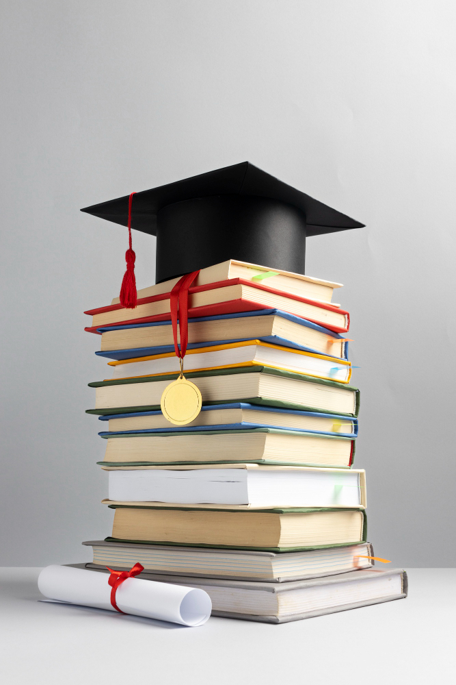 Graduation cap placed on a stack of books with a diploma scroll and medal on a white background.